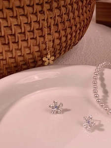 Close-up of a floral jewelry set with blue crystal inlay on a rustic woven background