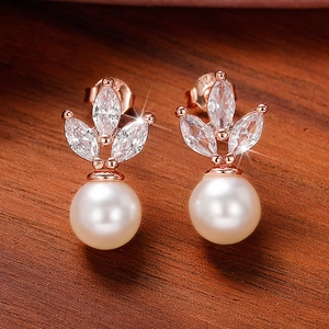 Macro shot of rose gold marquise zircon earrings with elegant round white pearls