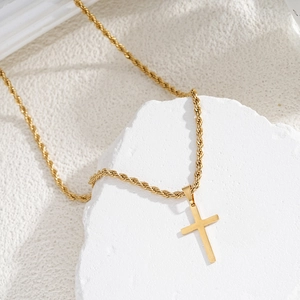 Gold stainless steel cross pendant necklace with heavy rope chain on stone texture