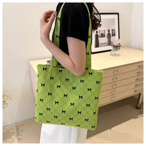 Dettaglio della borsa tote in velluto verde chiaro con fiocchi neri e motivo a rombi