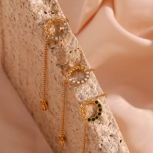 Detail of gold twist ring earrings with pearls and emerald green zircons on silk