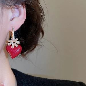 Close-up of red heart earrings with gold snowflake studs and zircons on model