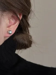 Primo piano di un orecchino a perla argentata indossato su modella per un look minimal