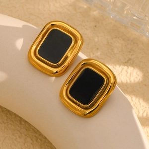 Vue macro de clous d'oreilles rectangulaires en acier plaqué or 18K avec onyx noir central
