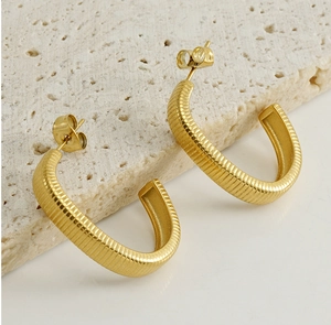 Macro shot of 18k gold plated C-shaped earrings with horizontal ribbed texture on stone