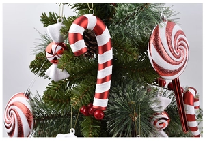 Close-up of red and white Christmas candy cane ornaments hanging on a pine tree branch