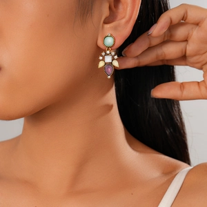 Gros plan d'une boucle d'oreille en or avec zircons colorés sur l'oreille du modèle