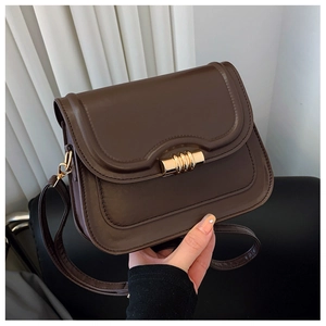 Détail d'une besace vintage en cuir marron foncé avec boucle métallique dorée cylindrique