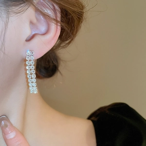 Close-up of elegant zircon tassel earrings with silver base on a model with soft lighting