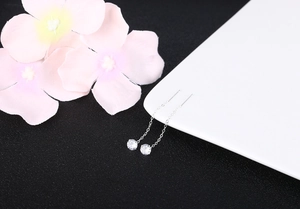 Detail of silver S925 drop earrings with zircon studs on an elegant white ceramic dish