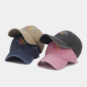 Detail of washed cotton baseball caps in multiple colors with rainbow letter embroidery