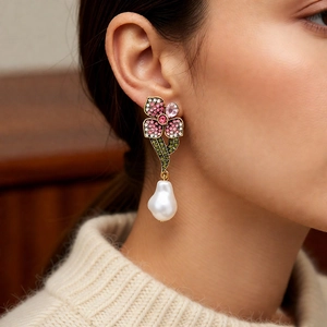 Détail de la boucle d'oreille fleurie avec cristaux et perle baroque sur modèle