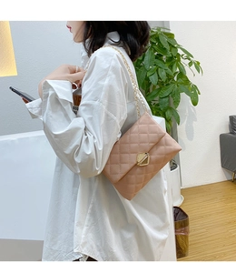 Detail of light pink quilted crossbody bag with gold chain strap and metal lock