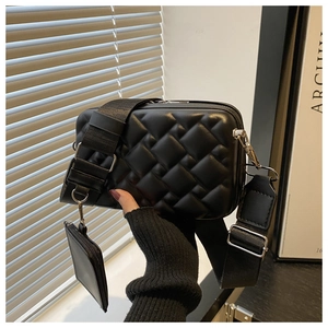 Detail of black quilted crossbody bag with adjustable wide strap and small detachable pouch