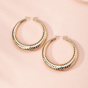 Detailed macro view of gold hoop earrings featuring geometric embossed patterns