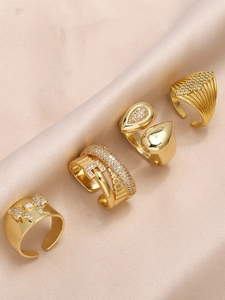 Detail view of four gold-plated rings with sparkling zircons on beige silk fabric