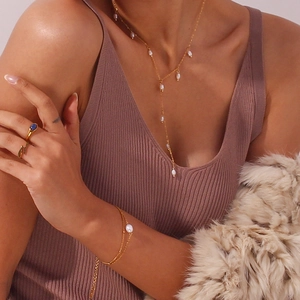 Gros plan d'un collier en Y doré avec perles d'eau douce et détails de glands sur un mannequin