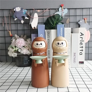Detail of cute Daruma Kaonashi piggy bank in brown and beige colors for kids