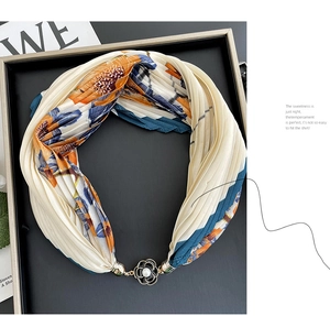Detail of pleated silk scarf featuring blue floral patterns and camellia pearl magnetic buckle