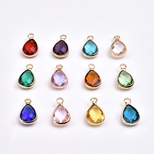 Detailed flat lay of 12 teardrop birthstone pendants with gold frames in various colors