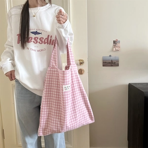 Model wearing a pink gingham canvas tote bag with white woven label in a casual setting
