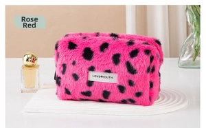 Detailed view of rose red leopard plush makeup bag with Love Youth label on white podium