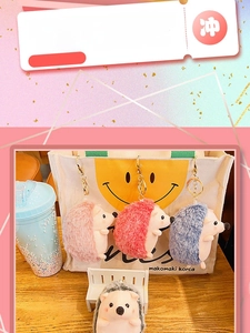 Detail of four colorful plush hedgehog keychains in pink, red, blue, and grey with metal clips
