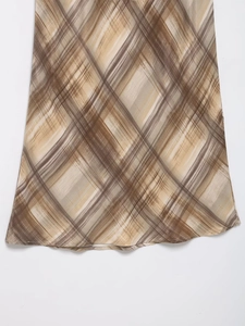Detail des Saums vom Satin-Midirock mit braunem und beigem Rautenmuster auf weißem Grund