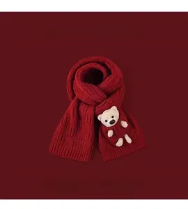 Close-up of red chunky knit scarf featuring a cute beige teddy bear doll ornament