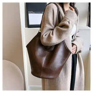 Detail view of large dark brown retro tote bag shown in a minimalist street style pose