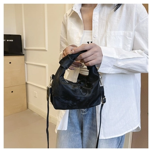 Detail of black glossy knotted handbag showing the silky texture and adjustable strap