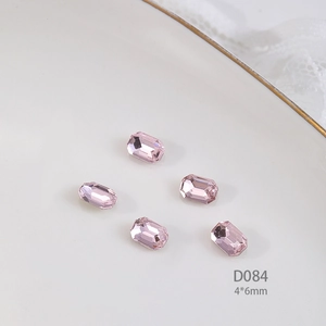 Macro shot of 4x6mm pink rectangle crystals on a white ceramic plate with lace background
