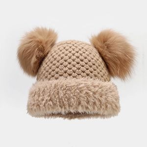 Detail view of khaki knit beanie with dual fur pom-poms and fluffy faux fur trim