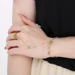 Detailed shot of 18k gold hand chain with turquoise beads and tree of life heart charm