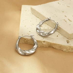 Polished silver twisted hoop earrings made of titanium steel on elegant beige stone blocks