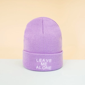 Close-up of purple beanie with white Leave Me Alone embroidery and soft knit texture