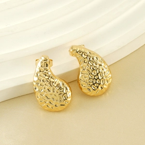Macro shot of gold-plated teardrop earrings featuring a textured hammered finish