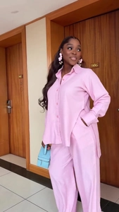 Detailed view of pink long sleeve slit shirt and wide leg trousers on a model