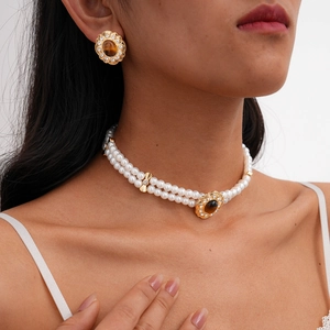 Close-up of vintage double-layer pearl necklace and earrings with tiger eye stone settings