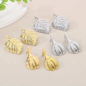 Macro shot of gold and silver leaf-shaped stainless steel earrings with textured details