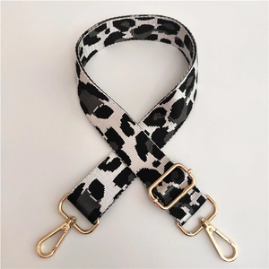 Detail of adjustable leopard print bag strap with gold metal hooks and weave texture