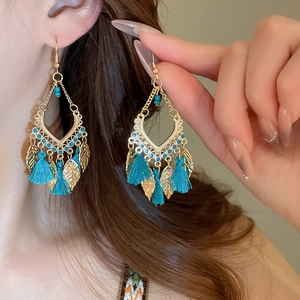 Detail of boho gold leaf earrings with blue tassels and beads shown on a model