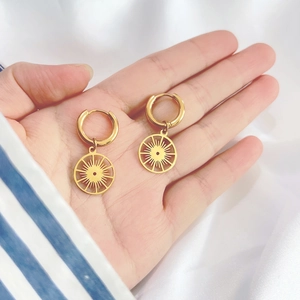 Handheld view of 18K gold starburst earrings showing real size and metallic texture
