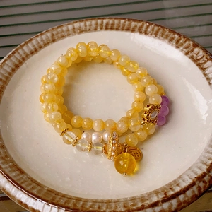 Detail view of multi-layer beaded bracelet with yellow citrine, pearls and Fu pendant