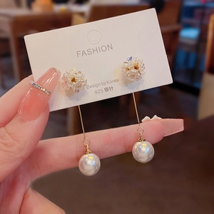 Detail of 925 silver needle drop earrings with pearl pendants and floral design