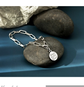 Macro detail of silver rectangular link chain bracelet with engraved Trust in the Lord pendant