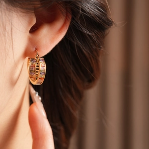 Close-up of a model wearing vintage gold cross square earrings with colorful gemstones