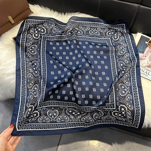 Détail d'un foulard en soie bleu marine à motif paisley sur un tapis en peluche
