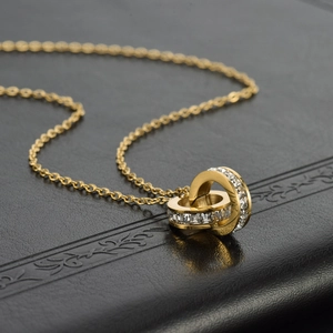 Golden titanium steel double ring necklace featuring cubic zirconia on a black leather background
