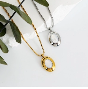 Detail of gold and silver oval shell pendants with thick box chains on stone textures